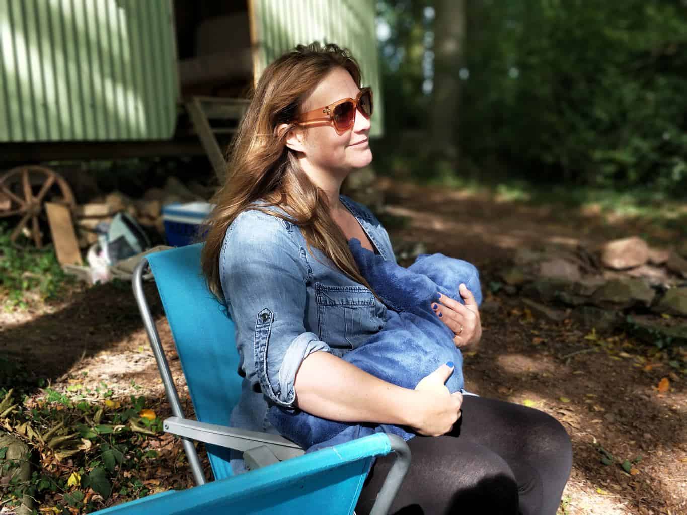 woman carrying a baby while sitting on a chair outside