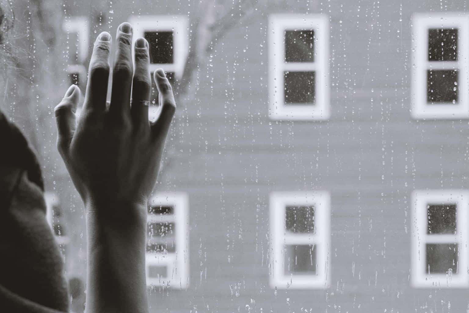 grayscale photo of a woman's hand on glass - depicting depression