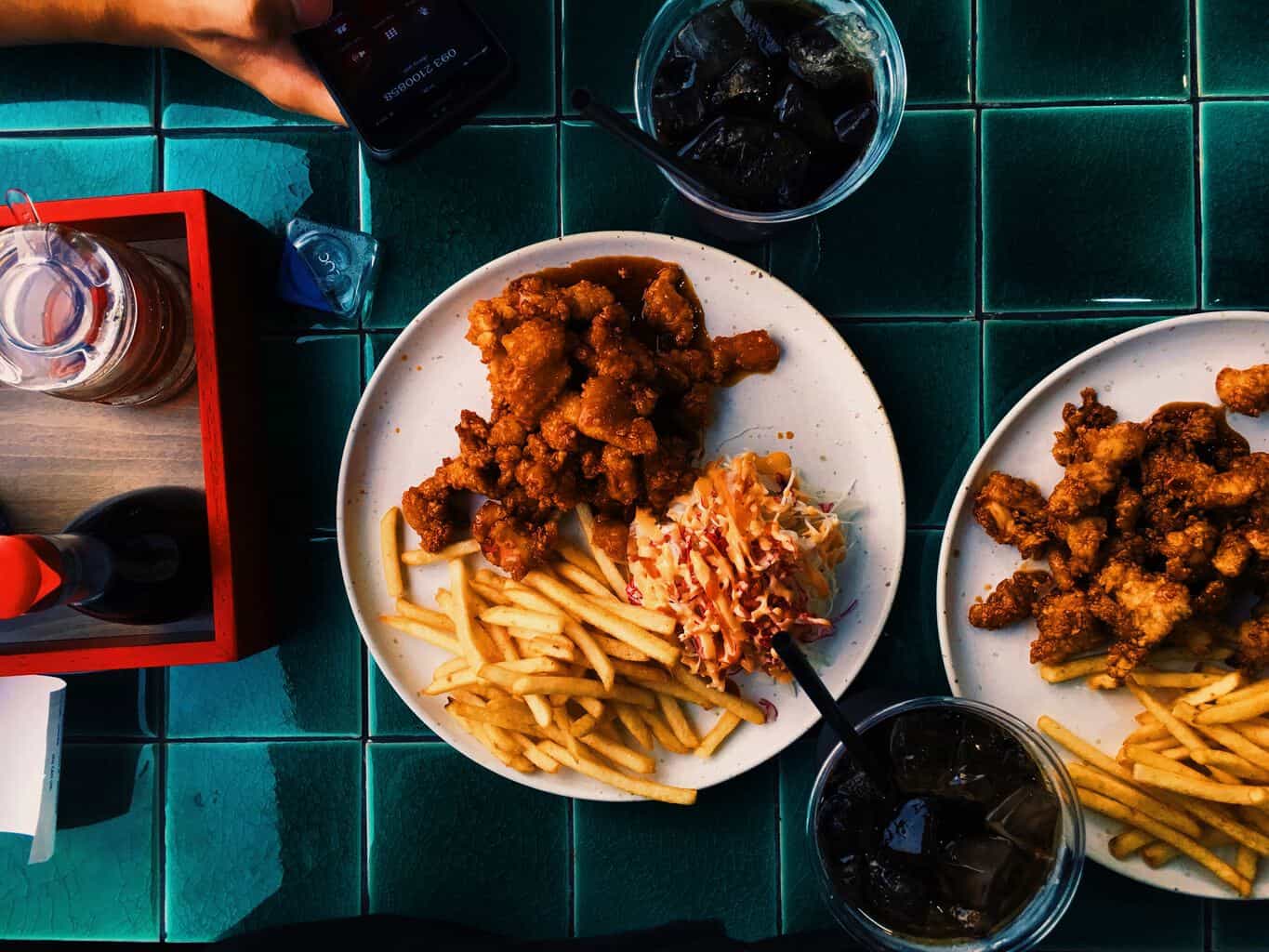 two plates of fried chicken and french fries