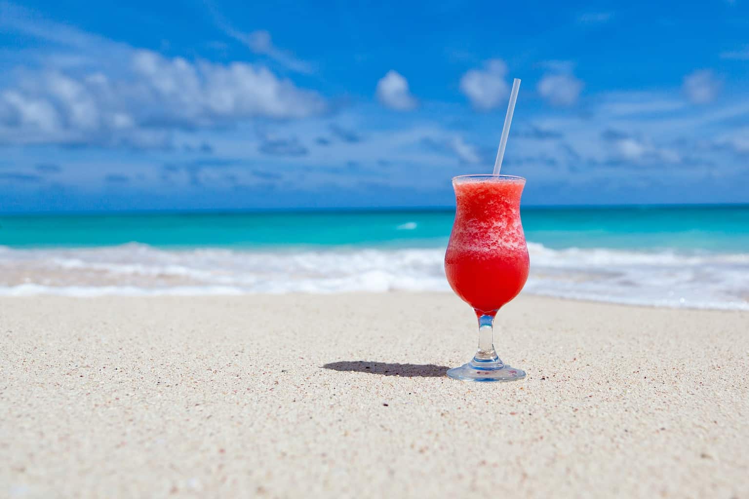 a glass of juice on a beach